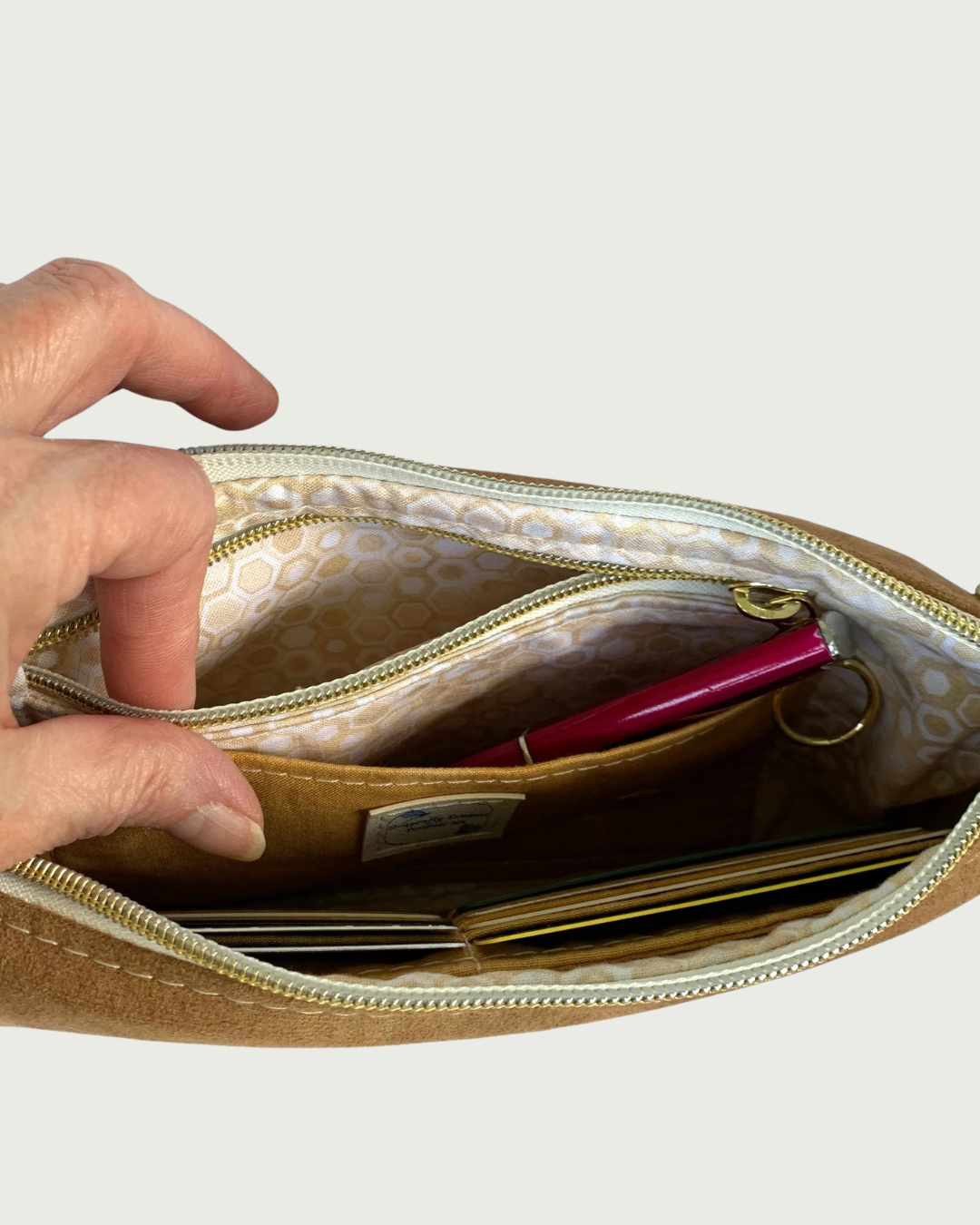 Handmade wristlet wallet interior closeup showing opened zippered pocket, a slip pocket, and some credit cards indicating there are card slots.