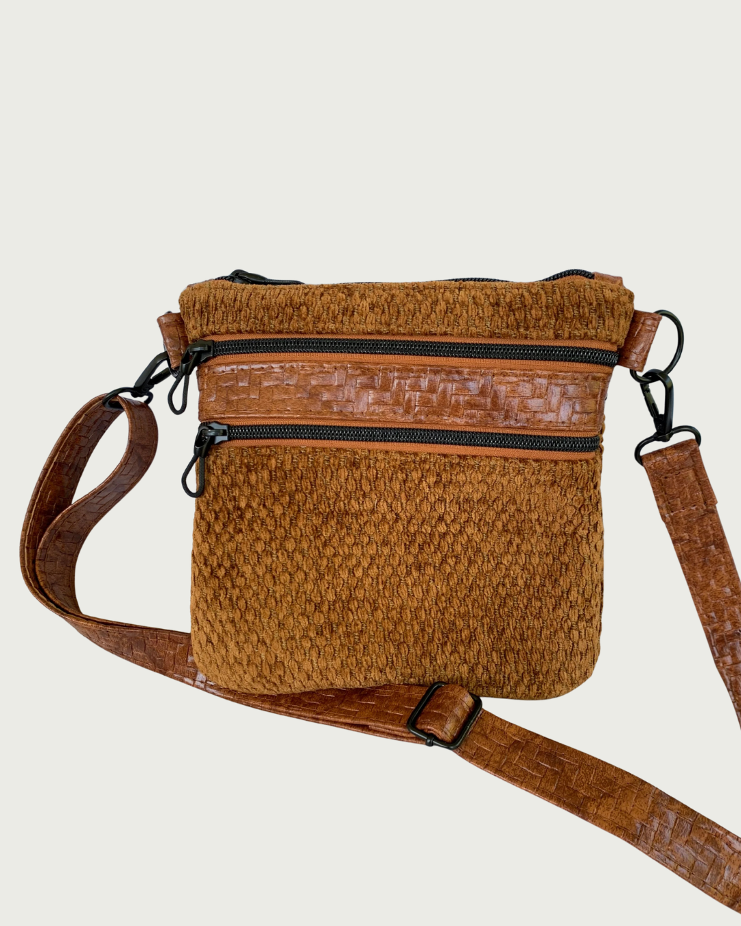 Handmade crossbody bag of brown chenille fabric with brown textured faux leather accents including an adjustable and detachable shoulder strap. Matt black hardware throughout as is on the two zippered pockets and the top zippered closure with rope zipper pulls.