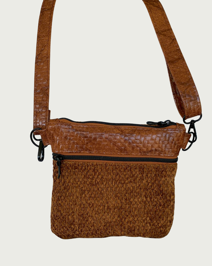 Handmade crossbody bag of brown chenille fabric with brown textured faux leather accents including an adjustable and detachable shoulder strap. Matt black hardware throughout as is on the zippered pocket and the top zippered closure with rope zipper pulls.