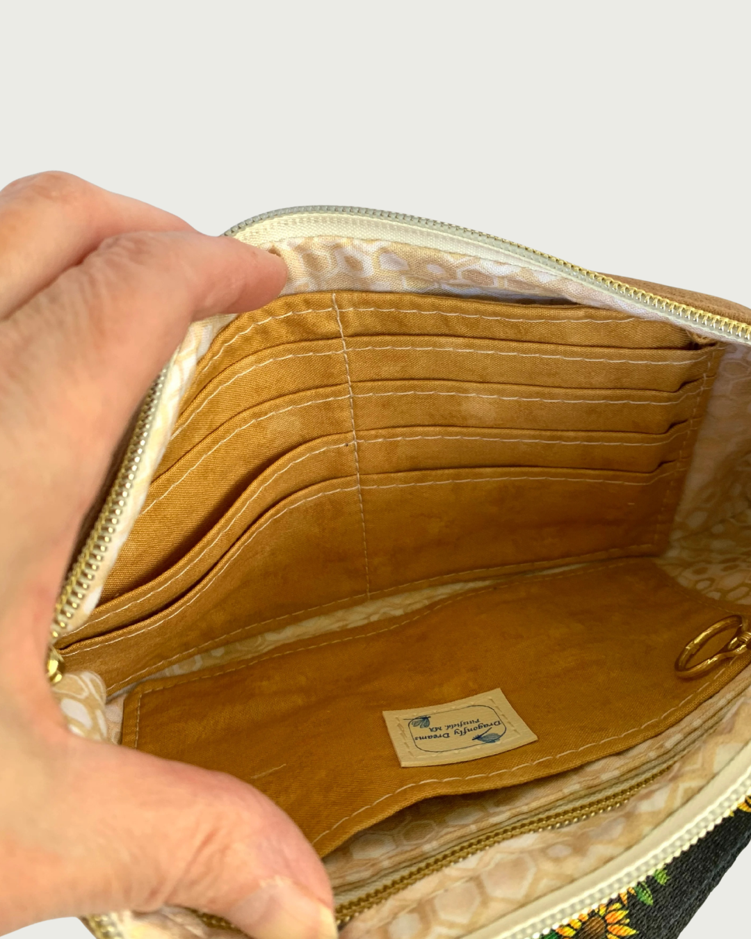 Interior of handmade wristlet showing 8 card slots, a slip pocket, and a zippered pocket. A Dragonfly Dreams Label is sewn onto the slip pocket.