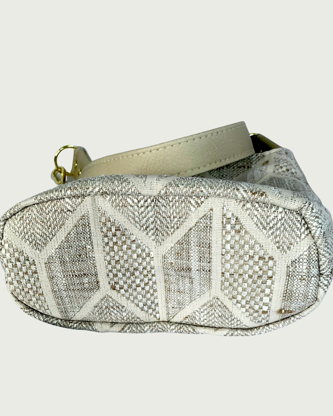 Handcrafted chevron slouchy shoulder bag in neutral colors with beige vinyl strap and trim. View of the bottom base.