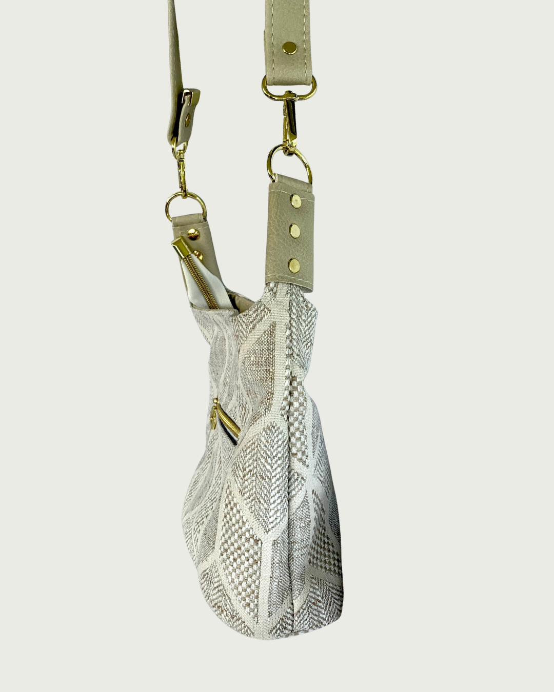 Handcrafted chevron slouchy shoulder bag in neutral colors with beige vinyl strap and trim shown from the side.