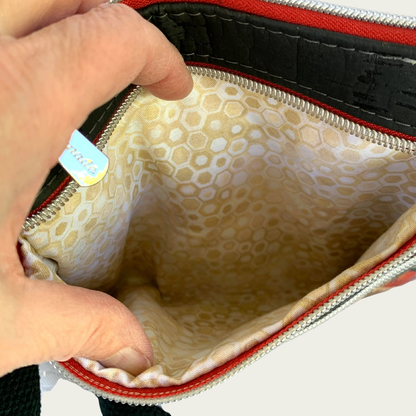 View of the inside of a pocket of a cork handbag. The lining is a geometric pattern in gold, white, and tan.