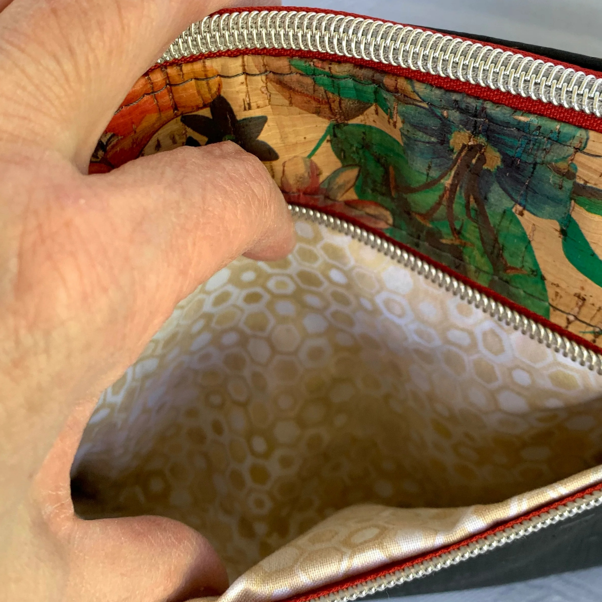 closeup view of the interior of a pocket in a floral cork handbag. The lining is a small geometric print in tan, gold, and white.