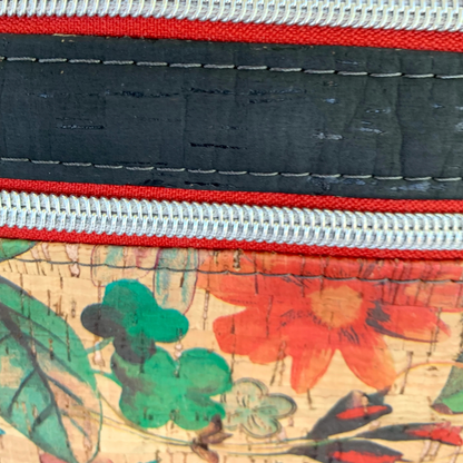 closeup of red zippers and nickel hardware on a Floral print and black cork crossbody bag.