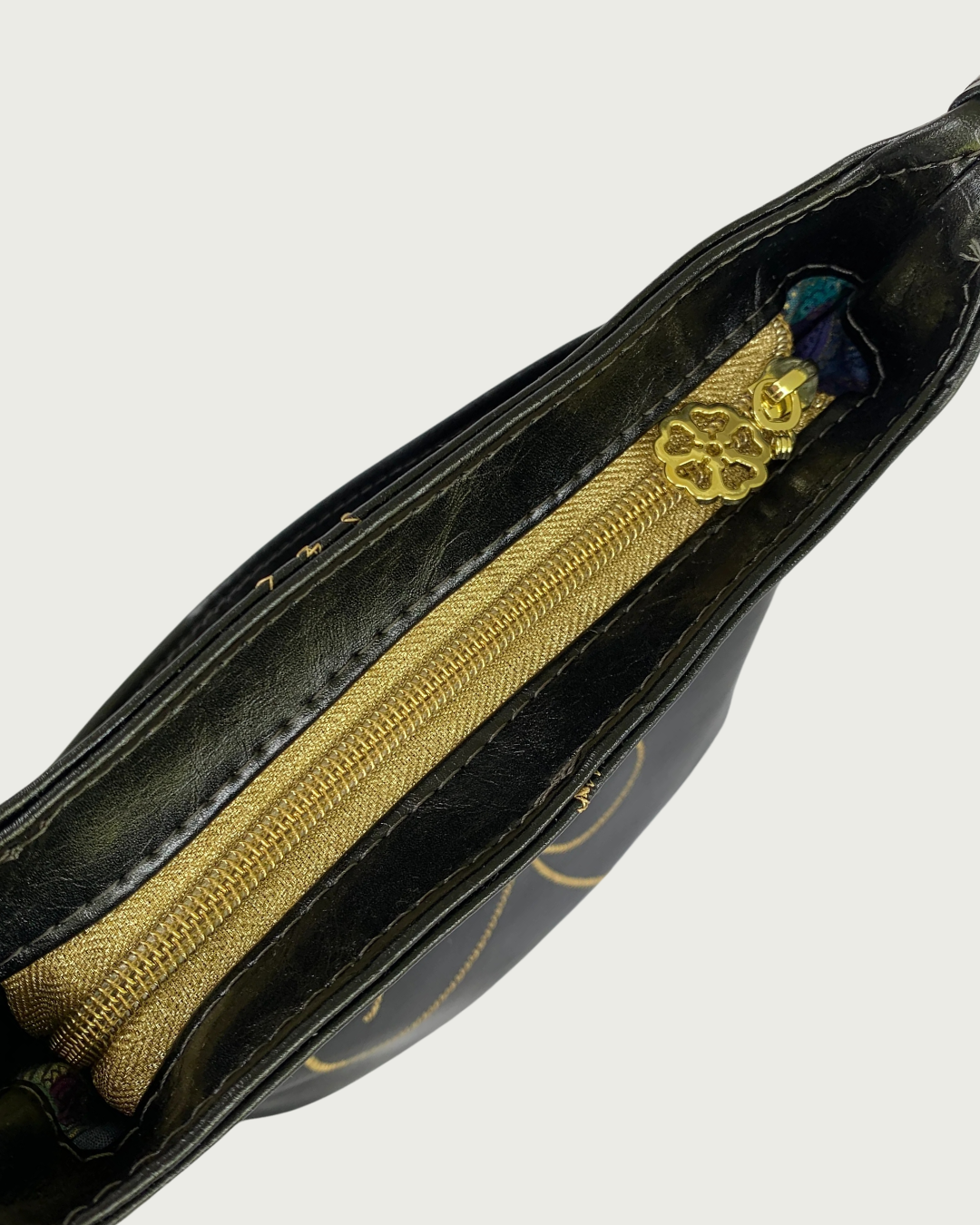 Handcrafted black vinyl slouchy shoulder bag with view of the top gold zippered closure with zipper pull resembling the design of the bag.