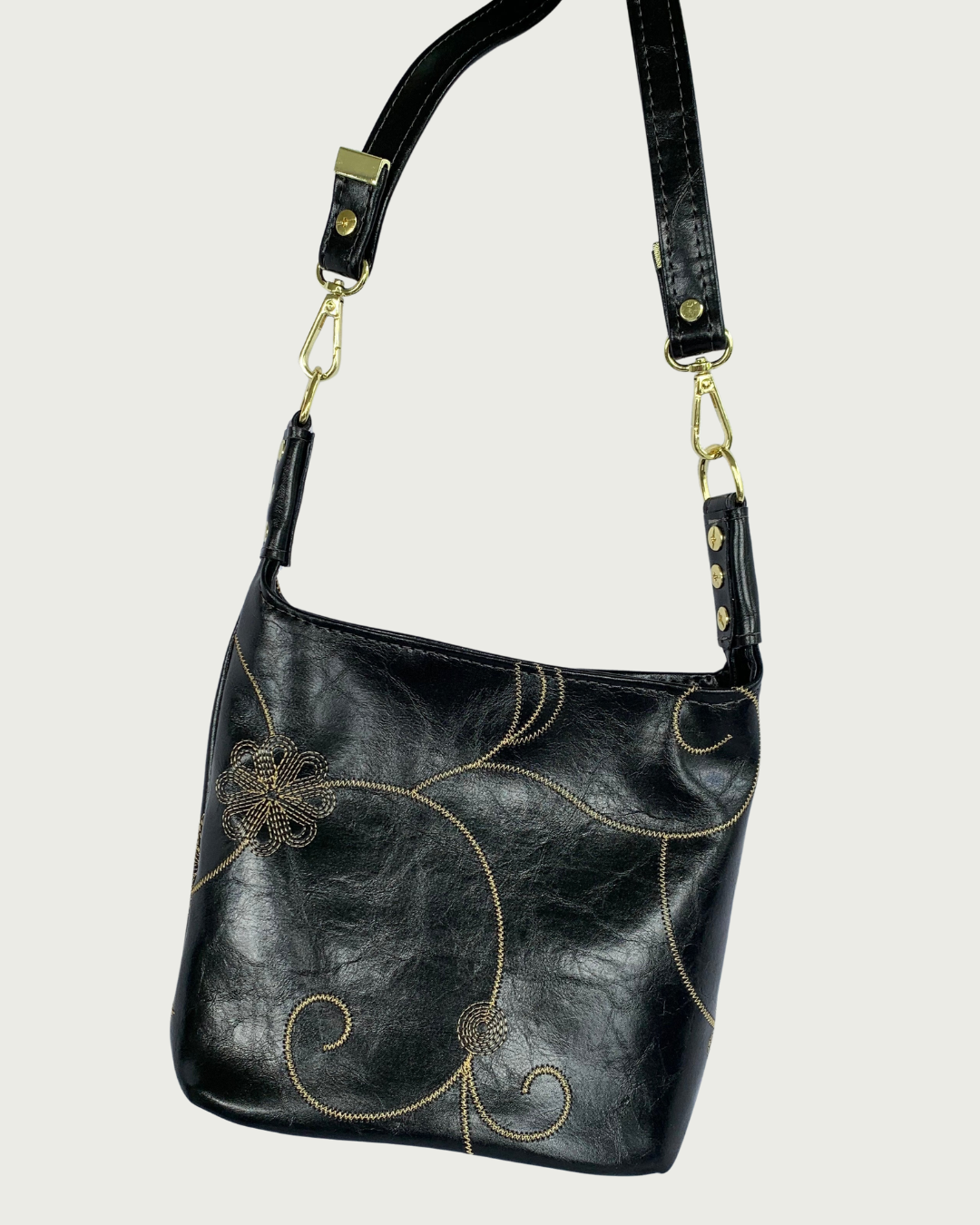 Handcrafted black vinyl slouchy shoulder bag with decorative gold stitching, gold hardware, and detachable strap.