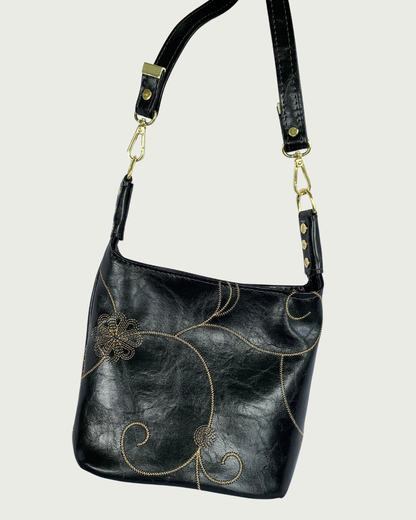 Handcrafted black vinyl slouchy shoulder bag with decorative gold stitching, gold hardware, and detachable strap.