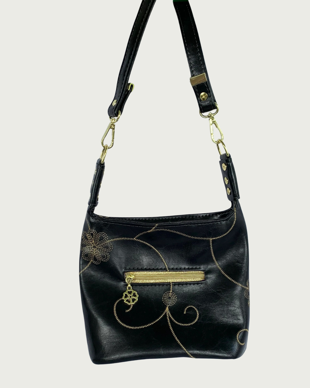 Handcrafted black vinyl slouchy shoulder bag with decorative gold stitching, a small exterior zippered pocket, gold hardware, and detachable strap.