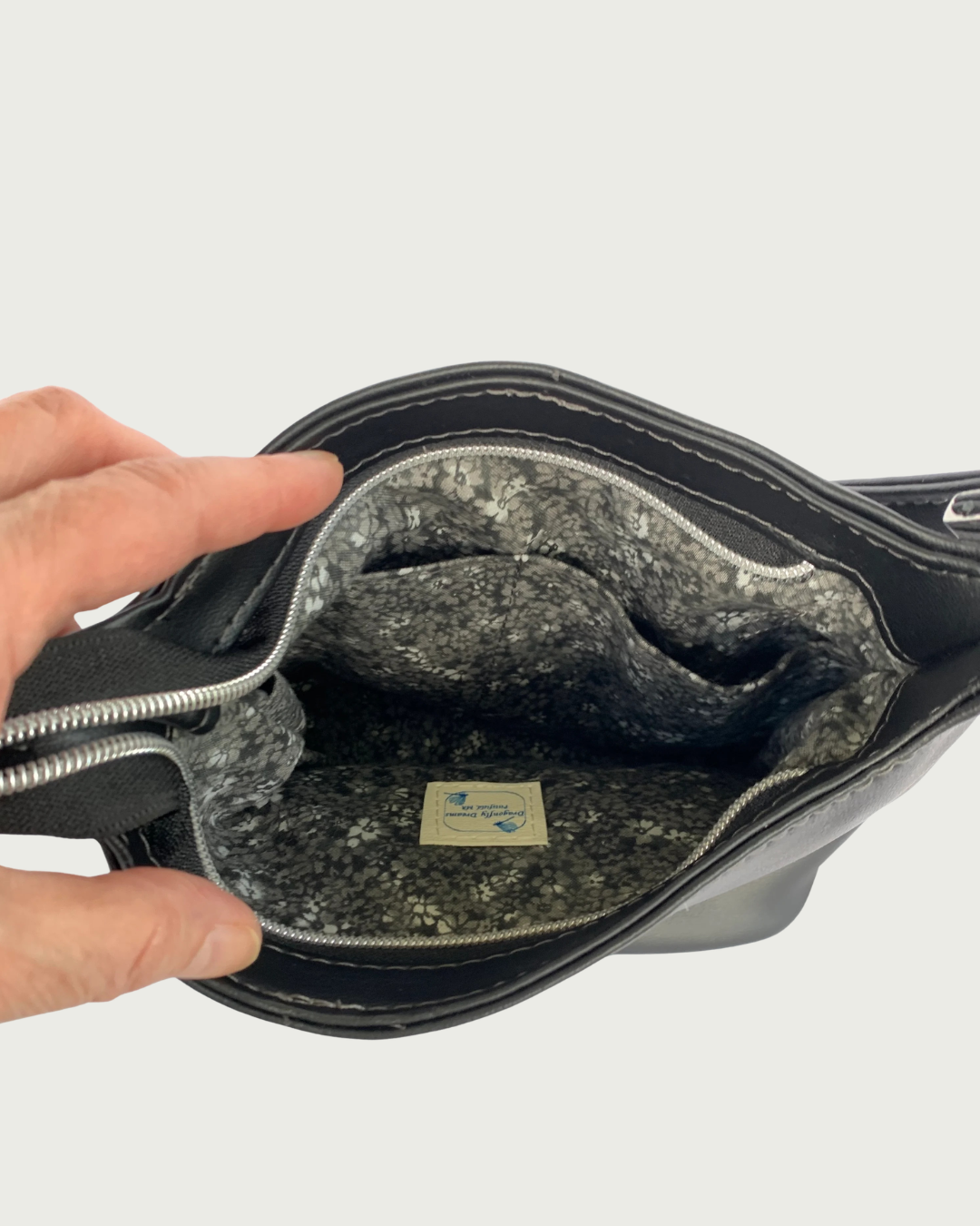 Handcrafted black vinyl slouchy shoulder bag with view of the interior with slip pockets. The lining is a black and gray calico and there is a label for Dragonfly Dreams sewn in.
