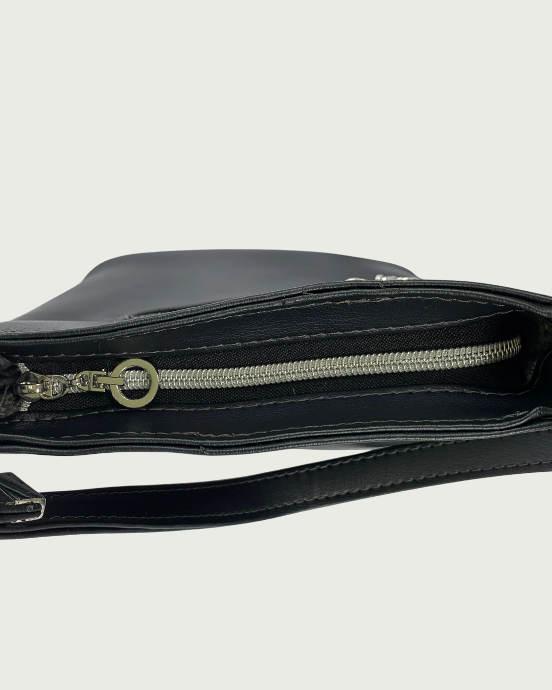 Handcrafted black vinyl slouchy shoulder bag with view of the top closure of a black zipper with nickel teeth and a nickel, dangling circle zipper pull.