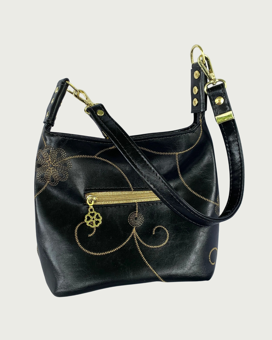 Handcrafted black vinyl slouchy shoulder bag with decorative gold stitching, a small exterior zippered pocket, gold hardware, and detachable strap.