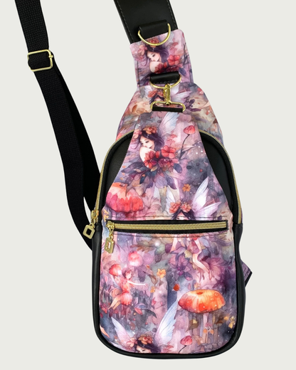 Handcrafted sling bag with a print of an enchanted forest with fairies and mushrooms in pinks and purples, grays and oranges. Water-resistant canvas bag with black faux leather accents with an adjustable wide black cotton webbing strap also repositional for left and right handed wear. All hardware is gold including the zipper teeth on black zipper tape. A front zipper pocket is shown as well as a front panel that unhooks with a swivel held onto a d-ring. Behind that is a curved zippered main compartment of 