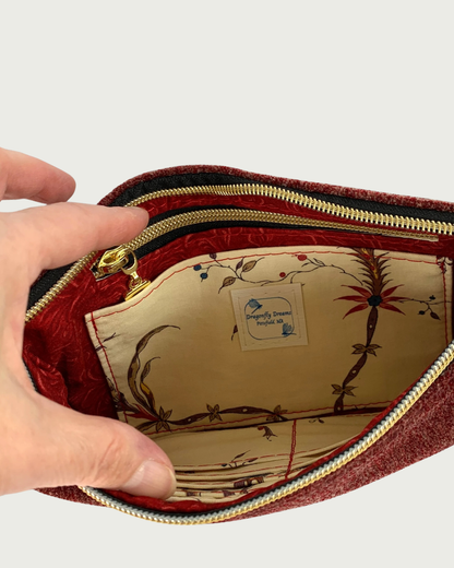 Handcrafted merlot chenille-like polyester wristlet wallet interior of coordinating solid and print fabrics. One side features a slip and zipper pocket combo with a Dragonfly Dreams label sewn in, and the other side partially reveals built-in card slots. Black zipper tape with gold-tone teeth and zipper pull are also shown.