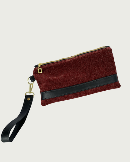 Handcrafted merlot chenille-like polyester wristlet wallet featuring black faux leather accents including a detachable wrist strap. The hardware is gold-tone such as on an open square pull and zipper teeth on black zipper tape.