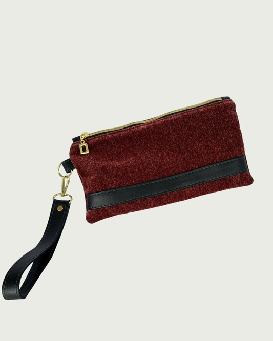 Handcrafted merlot chenille-like polyester wristlet wallet featuring black faux leather accents including a detachable wrist strap. The hardware is gold-tone such as on an open square pull and zipper teeth on black zipper tape.