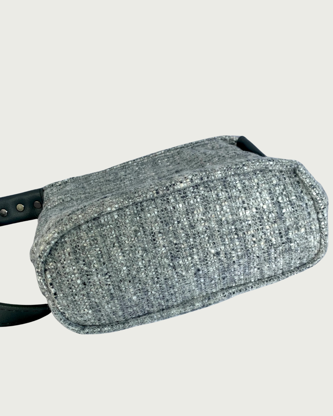 The exterior bottom of a gray wool-like shoulder bag.