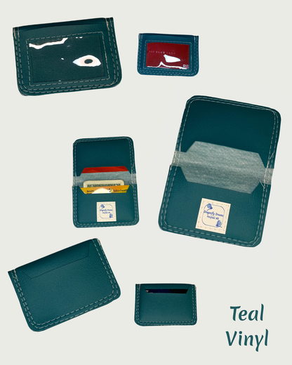 Handcrafted compact bifold wallet made from a teal marine vinyl. The wallet is shown in six different views, front, back and the inside when opened. One of each is shown empty, another of each is shown with cards and/or cash. A clear vinyl window pocket is evident in the views of the front.  The back views show a card slot. There is a card slot on both flaps of the inside of the wallet with a Dragonfly Dreams label sewn onto the bottom card slot and is shown in both of these views. The words Teal Vinyl are 