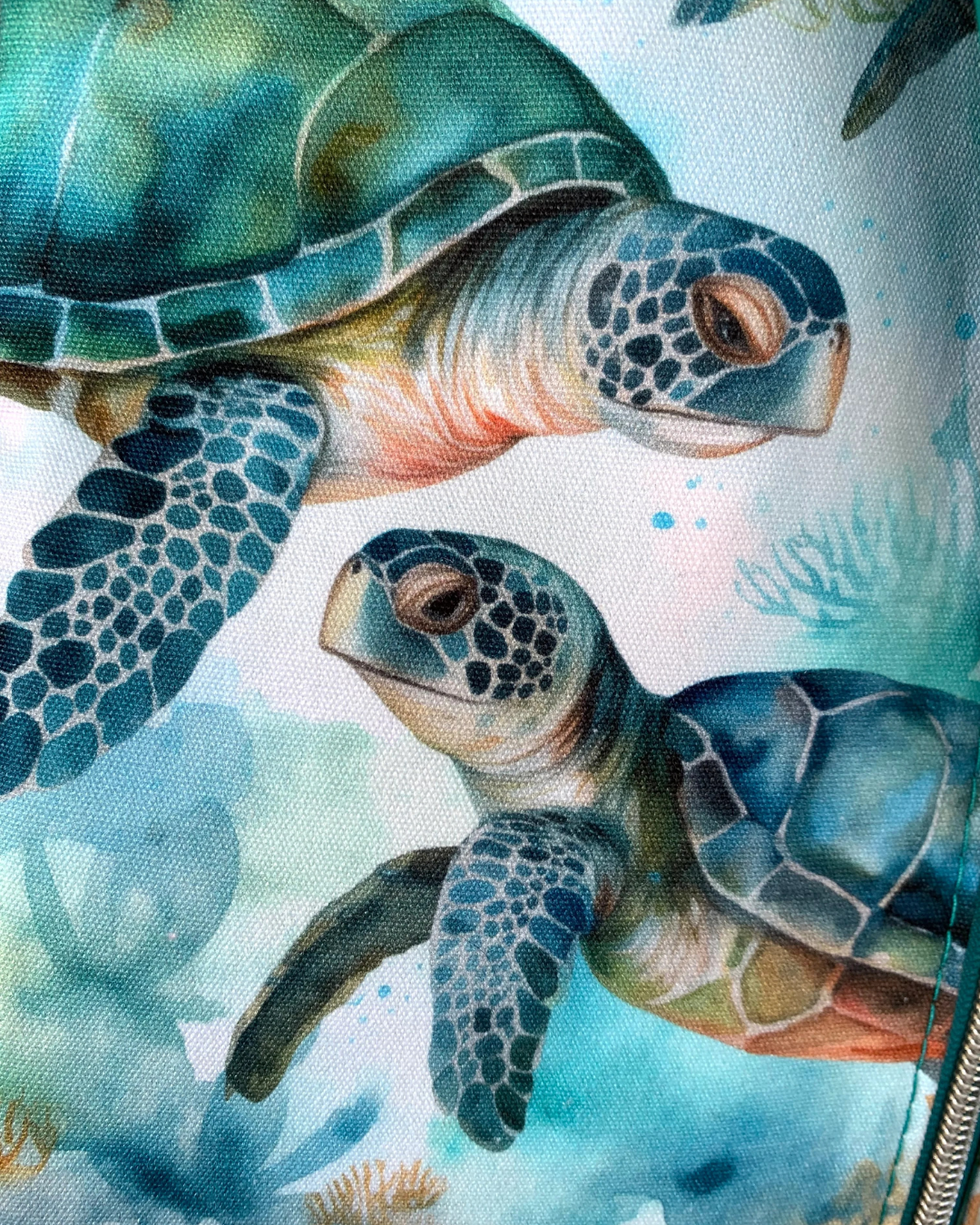 A close up view of water-resistant canvas with a print of sweet sea turtles in the colors of teal, aqua, green, brown, and white.