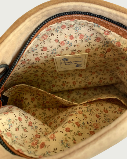 A Close-up view of the interior of a zippered purse showing the tan-colored lining with small pink flowers and 2 slip pockets.