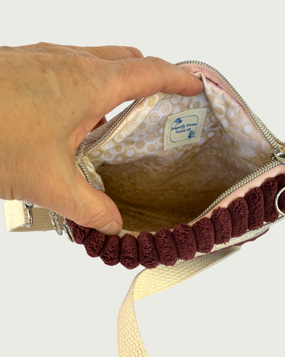 Top view of opened handmade maroon wide-wale crossbody bag showing a lining of tan, gold, and white geometric print with a Dragonfly Dreams label sewn in.