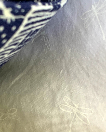 Handmade crossbody sling bag interior lining of white dragonflies on white cotton fabric background. Part of the slip pocket made from off-white houses and picket fences on navy background can be seen.