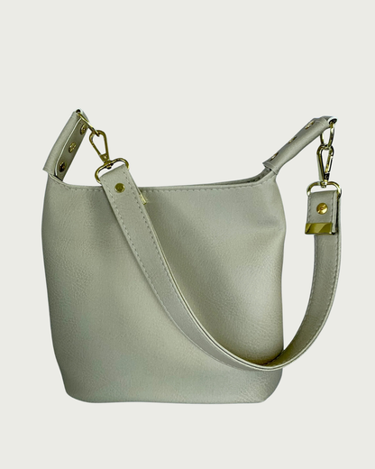 A solid beige faux leather shoulder bag with gold hardware and detachable strap as seen from front or back-wearer's choice.