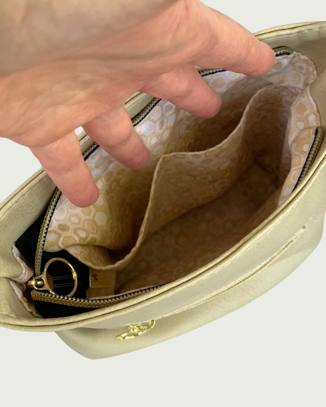 A closeup of a solid beige faux leather slouchy shoulder bag interior lining with 2 slip pockets.