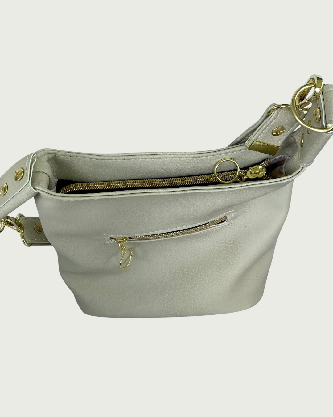 A solid beige faux leather shoulder bag with small exterior zippered pocket as seen from above looking down at the recessed zipper closure.