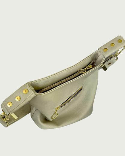 A solid beige faux leather slouchy shoulder bag with small exterior zippered pocket as seen from above looking down at the recessed zipper closure.