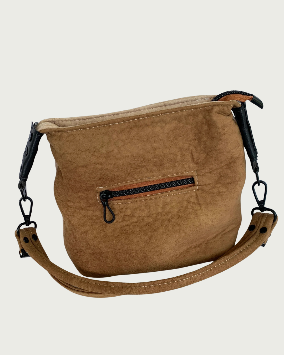 A brown suede shoulder bag with a brown  strap, matt black hardware, and small zippered pocket.
